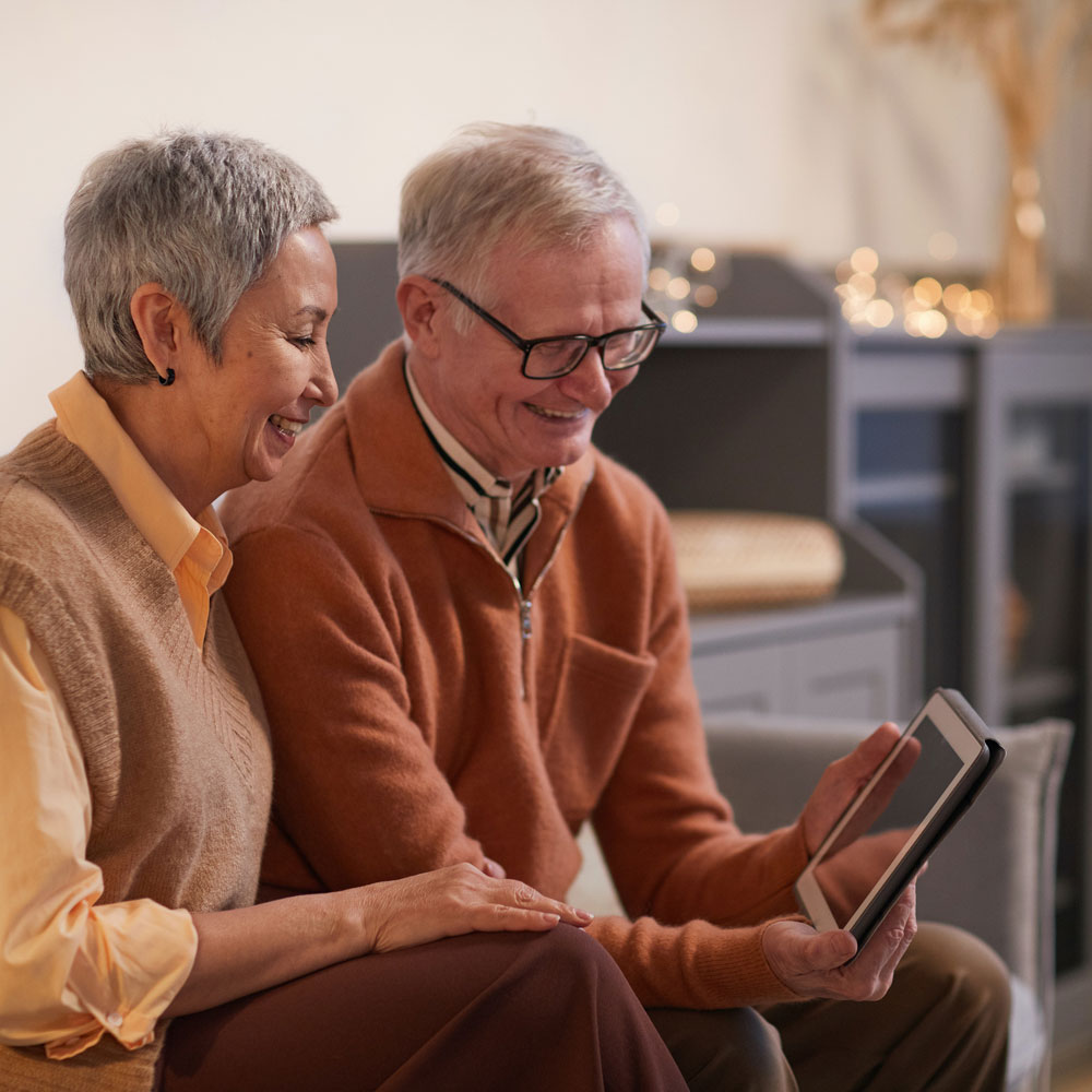 senior couple wearing glasses with a tablet